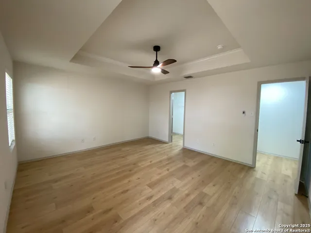 an empty room with wooden floor and ceiling fan