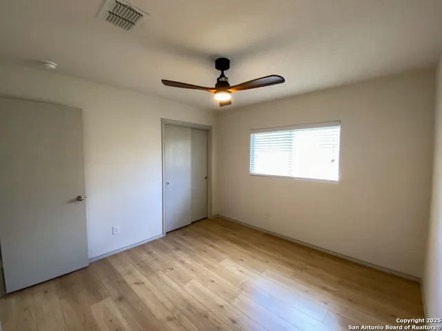 a view of empty room with wooden floor and fan