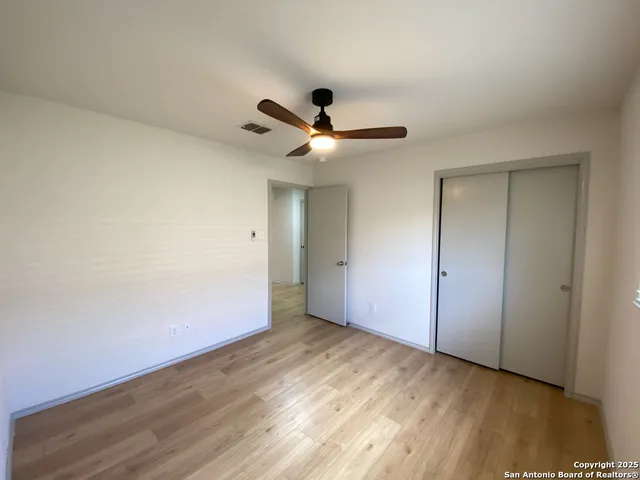 an empty room with wooden floor and ceiling fan
