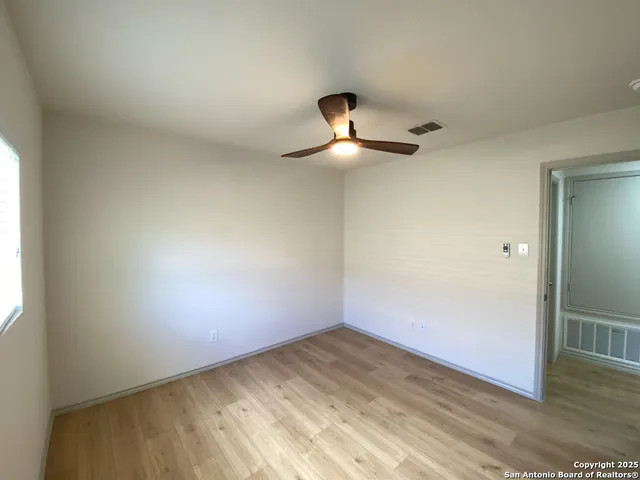 an empty room with a ceiling fan and window