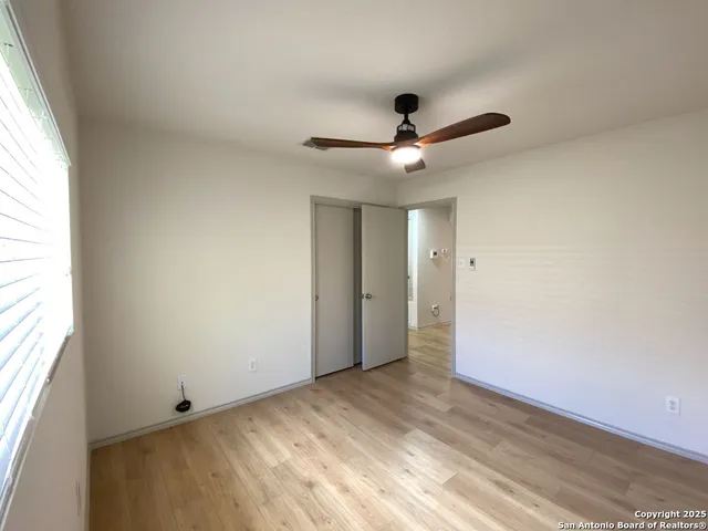an empty room with a window and a ceiling fan
