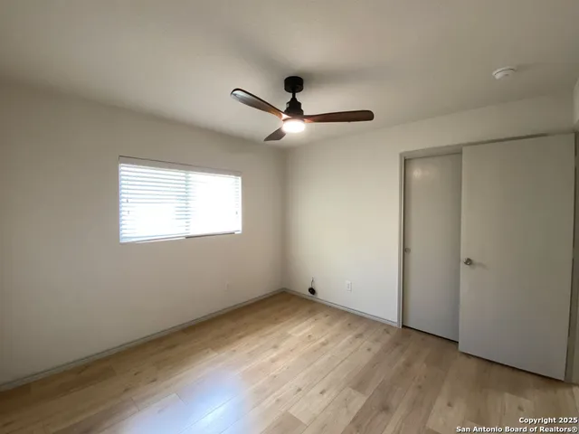 a view of empty room with wooden floor and fan
