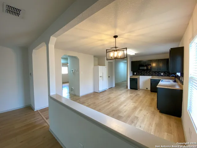 a large kitchen with kitchen island granite countertop a sink and a stove top oven with wooden floor