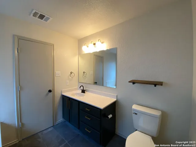 a bathroom with a sink vanity mirror and toilet