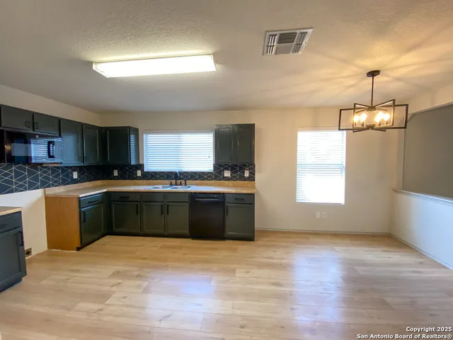 a large kitchen with stainless steel appliances granite countertop a stove a sink and a wooden floors