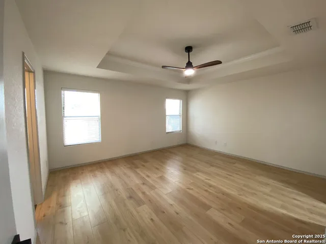 an empty room with wooden floor and windows