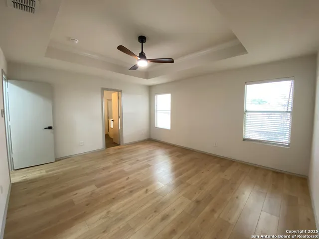 a view of an empty room with a window and wooden floor