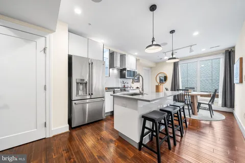 a kitchen with stainless steel appliances a dining table chairs stove refrigerator and cabinets