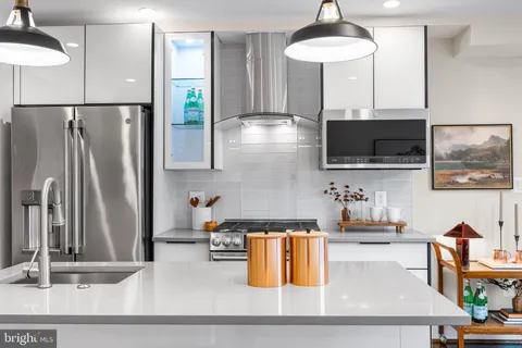 a kitchen with stainless steel appliances kitchen island granite countertop a refrigerator a stove and a sink with wooden floor