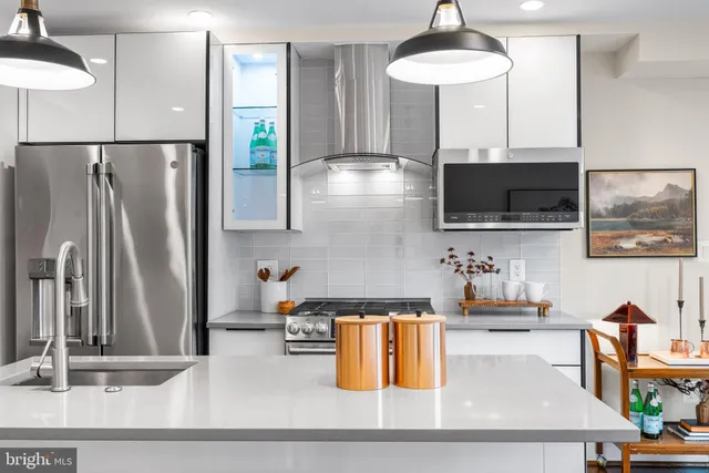 a kitchen with stainless steel appliances kitchen island granite countertop a refrigerator a stove and a sink with wooden floor