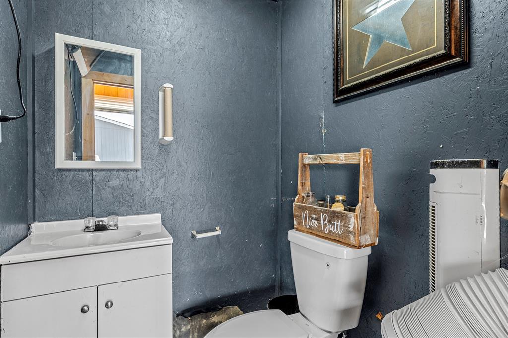 602 3rd Street Abbott, TX 76621 - Photo 31 of 40 Corner vanity with integrated sink, wall-mounted mirror, and wall-mounted light fixture