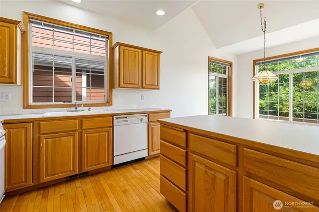 a view of a kitchen counter top space with stainless steel appliances wooden floor and cabinets