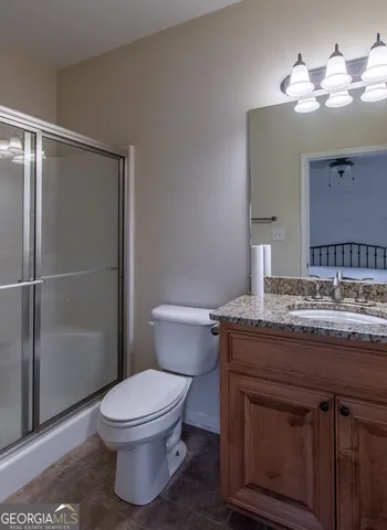 a bathroom with a granite countertop toilet a sink and a mirror