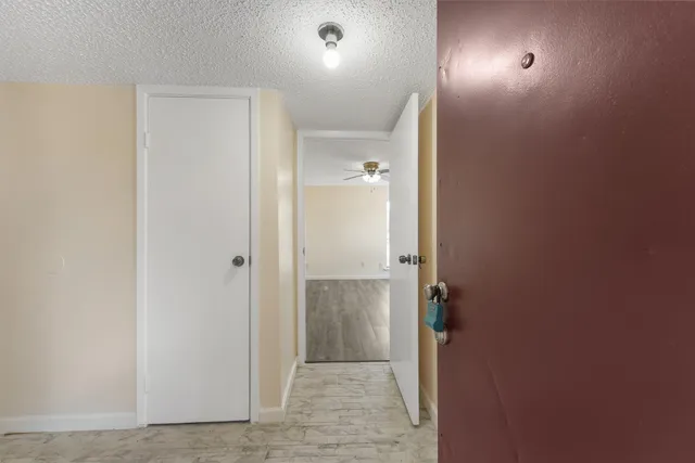 an empty room with wooden floor fan and windows