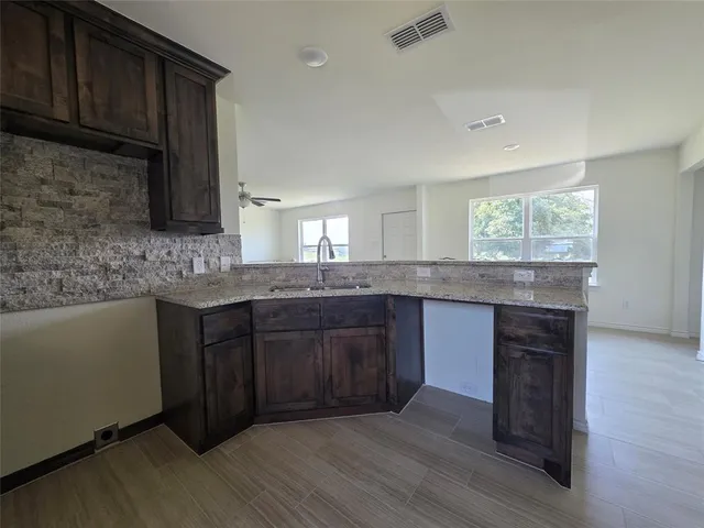 a kitchen with granite countertop wooden cabinets a sink and dishwasher