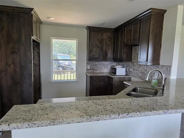 a kitchen with granite countertop a sink stove and cabinets