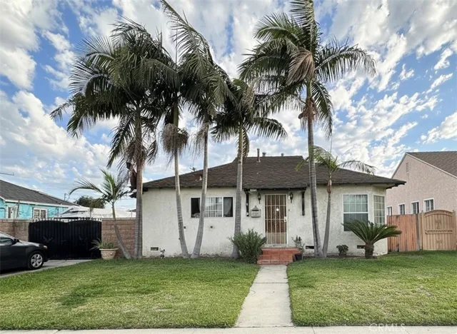 a view of a white house with a yard and palm trees