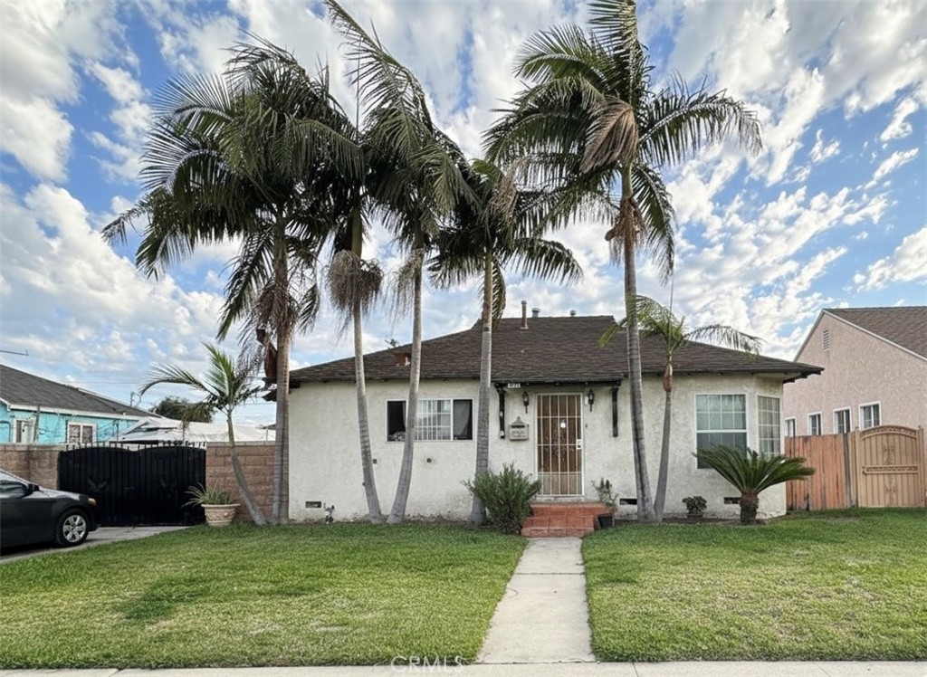 a view of a white house with a yard and palm trees