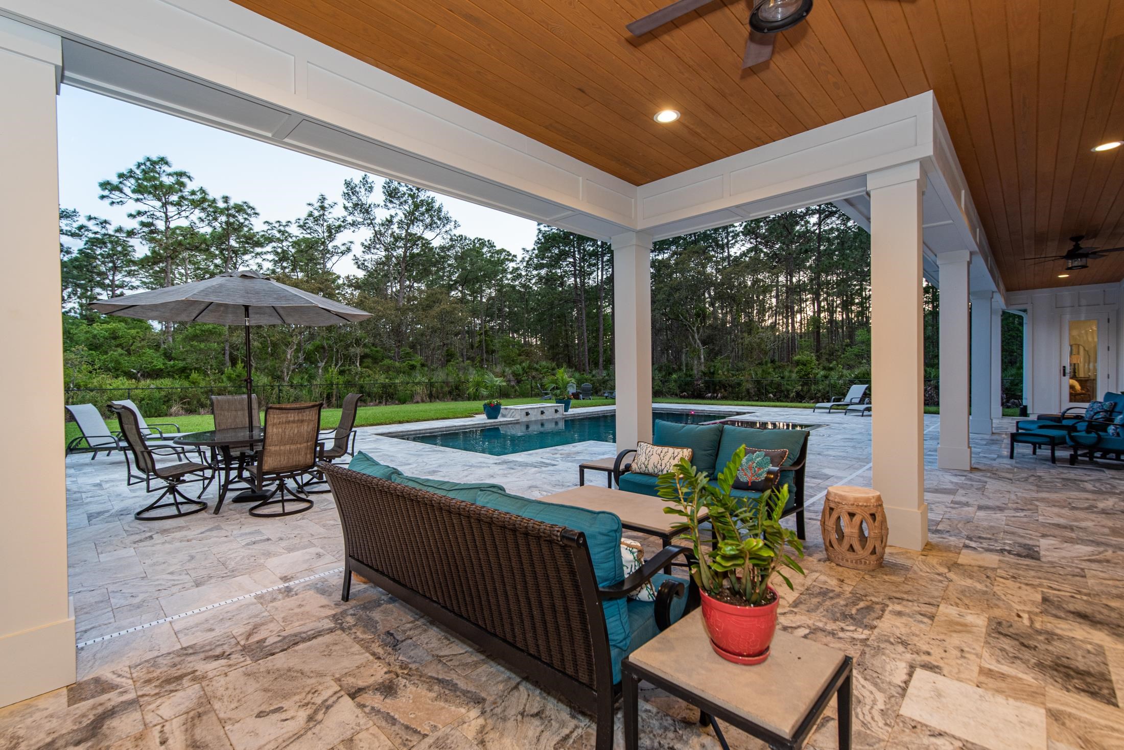 1015 Poinsettia Road St. Augustine, FL 32086 - Photo 15 of 50 a view of a patio with a dining table and chairs under an umbrella with a small yard
