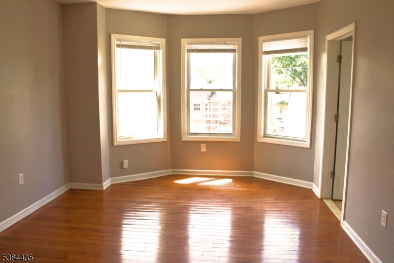 104 South 12th Street, Unit 3 Newark, NJ 07107 - Photo 2 of 12 a view of an empty room with wooden floor and a window