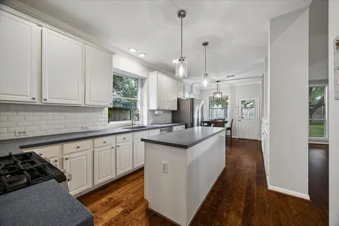 a kitchen with stainless steel appliances granite countertop a sink a stove and a wooden floor