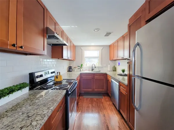 a kitchen with stainless steel appliances granite countertop a refrigerator a stove top oven a sink and dishwasher