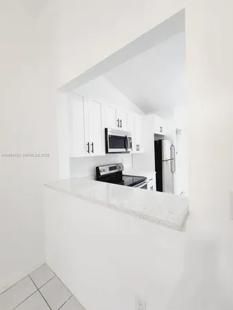 a kitchen with stainless steel appliances a refrigerator a stove a microwave and white cabinets