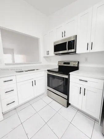 a kitchen with stainless steel appliances white cabinets and a stove top oven