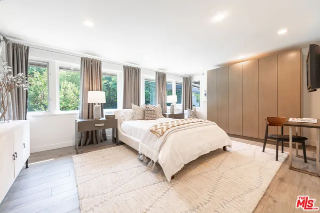 a bedroom with a bed and large windows