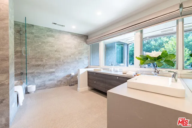 a bathroom with a sink a mirror and a bathtub next to a window