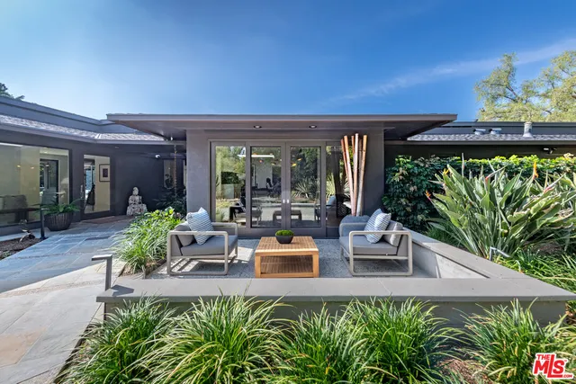 a view of a patio with table and chairs potted plants and floor to ceiling window