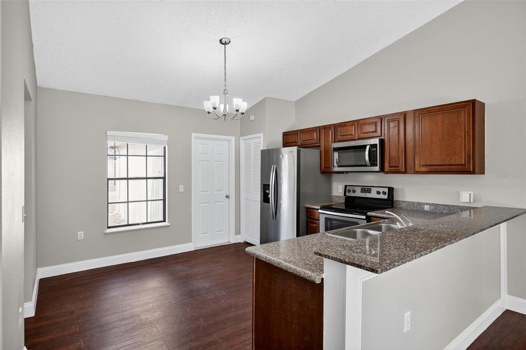 2737 East Dorchester Drive Deltona, FL 32738 - Photo 16 of 32 a kitchen with stainless steel appliances granite countertop a sink dishwasher stove and microwave with wooden floor