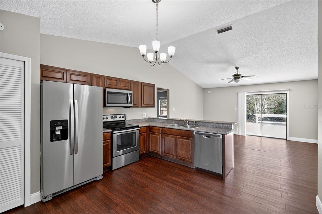 2737 East Dorchester Drive Deltona, FL 32738 - Photo 17 of 32 a kitchen with stainless steel appliances granite countertop a refrigerator a stove a sink and a chandelier
