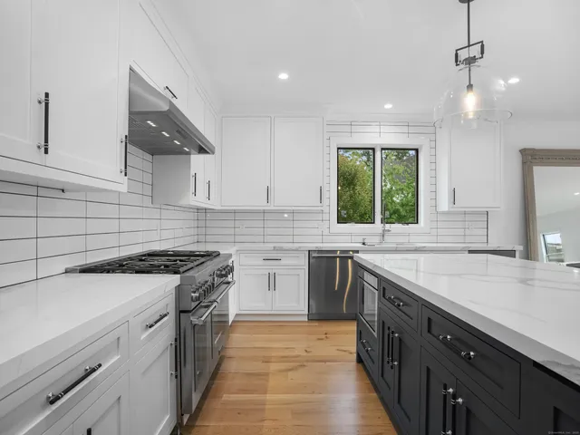 a kitchen with stainless steel appliances granite countertop a stove and a wooden floors