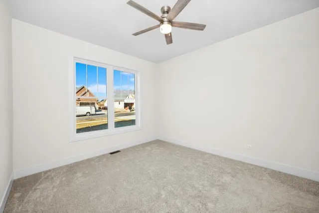 an empty room with a window and ceiling fan