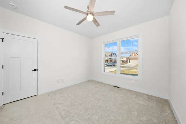 an empty room with windows and fan