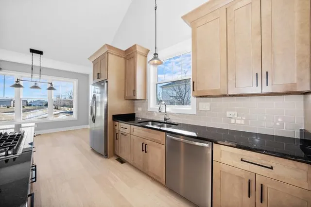 a kitchen with stainless steel appliances granite countertop a sink a stove and a wooden floors