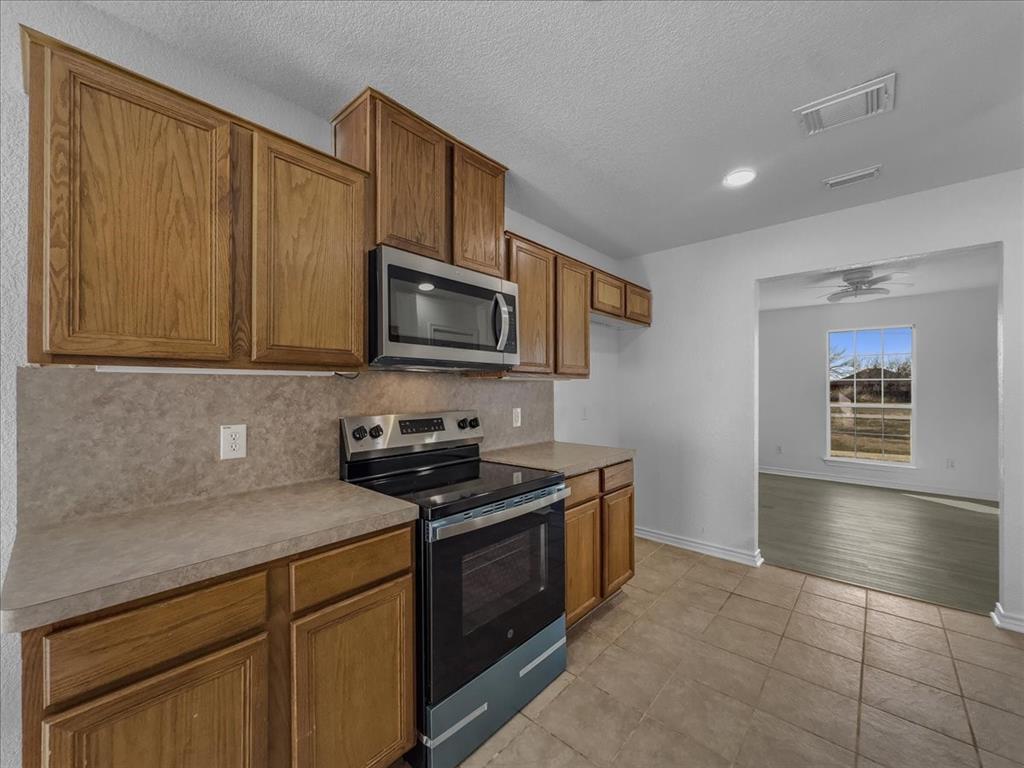 1101 Savanh Street Venus, TX 76084 - Photo 10 of 29 New range and microwave in kitchen with view of dining room