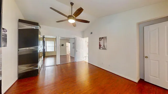 an empty room with wooden floor closet and windows