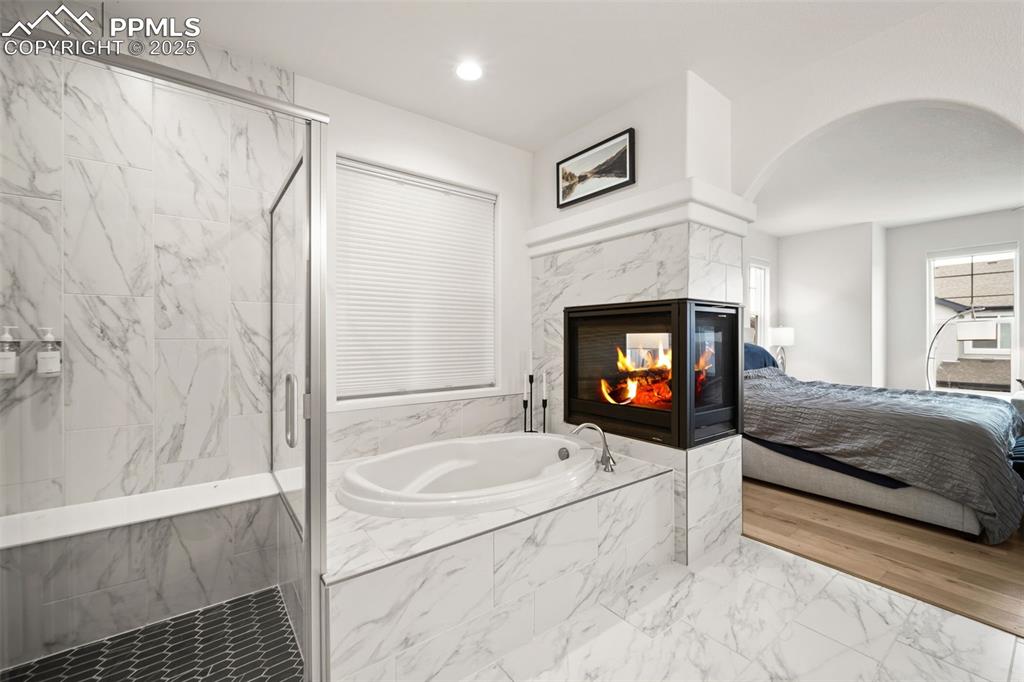 4661 Horse Gulch Loop Colorado Springs, CO 80924 - Photo 35 of 48 a bathroom with a sink a bathtub and a fireplace