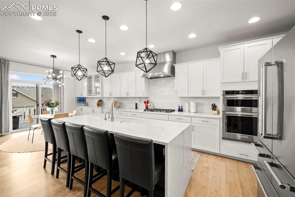 4661 Horse Gulch Loop Colorado Springs, CO 80924 - Photo 8 of 48 a kitchen with stainless steel appliances a kitchen island a stove a table and chairs in it
