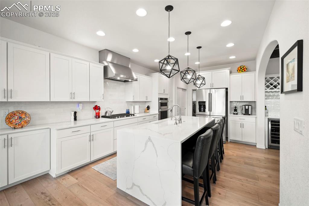 4661 Horse Gulch Loop Colorado Springs, CO 80924 - Photo 9 of 48 a kitchen with stainless steel appliances kitchen island a white cabinets and wooden floor