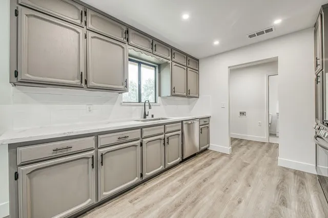 a view of a sink and dishwasher with wooden floor