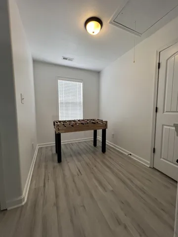 a view of an empty room with a window and wooden floor