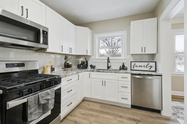 a kitchen with stainless steel appliances granite countertop a stove a sink and a microwave