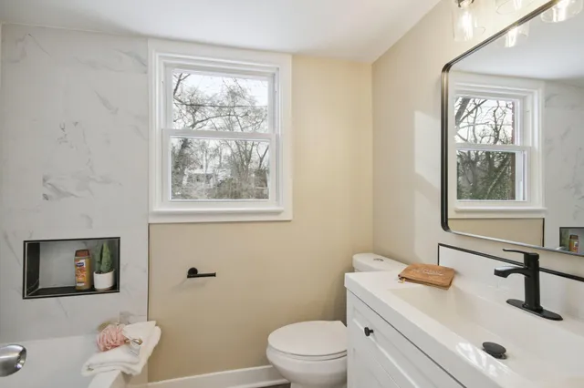 a bathroom with a granite countertop sink mirror and a window