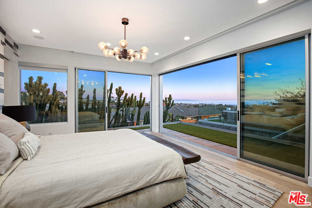 1239 Las Pulgas Road Pacific Palisades, CA 90272 - Photo 3 of 54 a bed sitting in a spacious bedroom next to a large window with a garden view