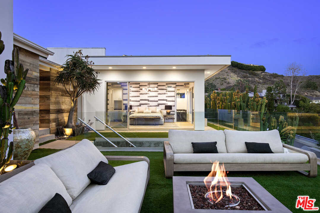 1239 Las Pulgas Road Pacific Palisades, CA 90272 - Photo 44 of 54 a view of a patio with couches table and chairs under an umbrella with a fire pit