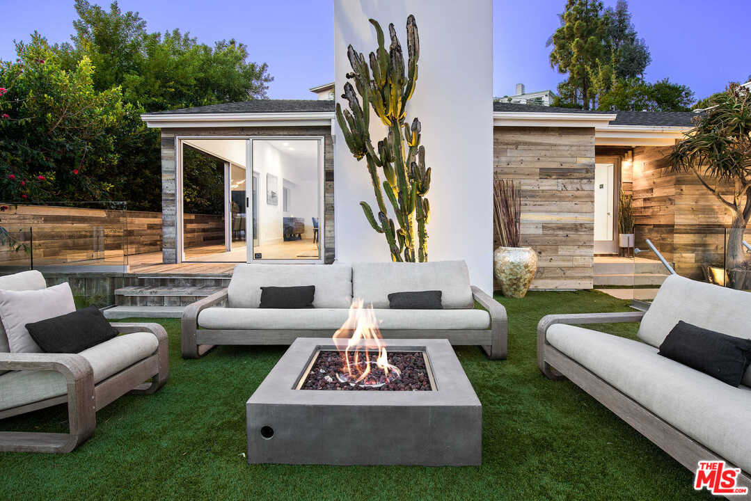 1239 Las Pulgas Road Pacific Palisades, CA 90272 - Photo 45 of 54 a view of a patio with couches and a table and chairs with plants and trees