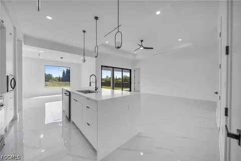 a large white kitchen with a large window a sink and stainless steel appliances